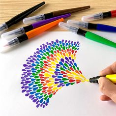 a person is drawing with markers and crayons