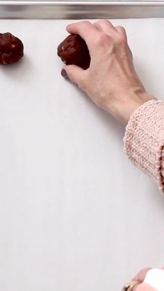 two hands reaching for chocolate cookies on a white surface