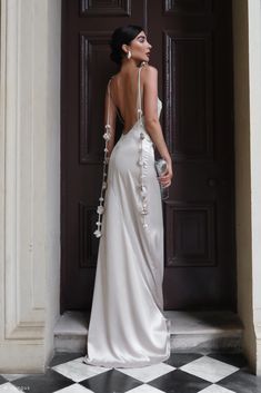 a woman standing in front of a door wearing a white dress