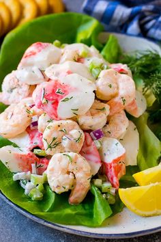 a plate with shrimp salad and lemon wedges