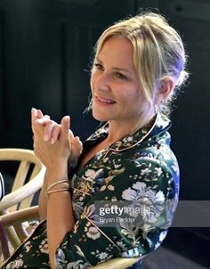 a woman sitting at a table with her hands clasped