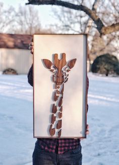 a person holding up a wooden cut out of a giraffe