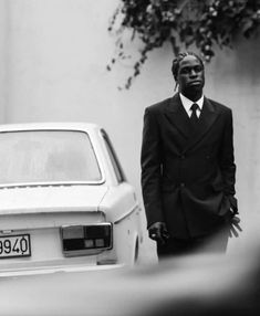 a man in a suit standing next to a white car