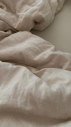 an unmade bed with white sheets and pillows