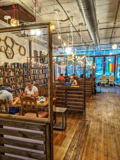 people sitting at tables in a library with lots of bookshelves and shelves full of books