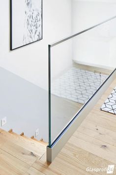 a glass handrail in the corner of a room with wood flooring and white walls