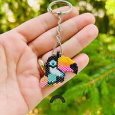 a hand holding a key chain with a toucan bead design on it