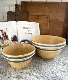 two bowls sitting on top of a counter next to an open book