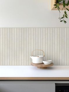 two white cups on a wooden tray sitting on top of a counter