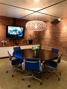 a round table with blue chairs in front of a flat screen tv on the wall