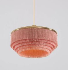 a pink and gold chandelier hanging from a ceiling fixture with fringes on it