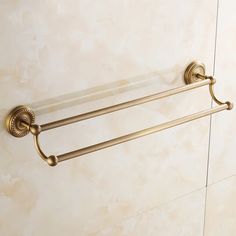 an antique brass towel rack with glass shelves on the wall and marble tile flooring