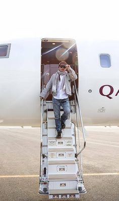 a man is stepping off an airplane with his hand in his hair and sunglasses on