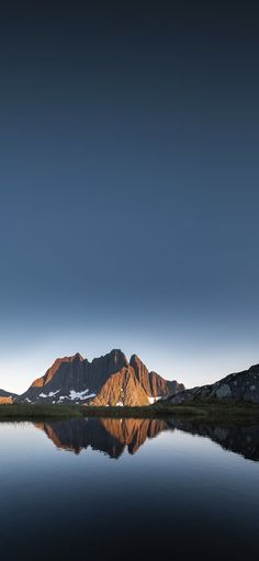 the mountains are reflected in the still water at dusk, while the sky is blue