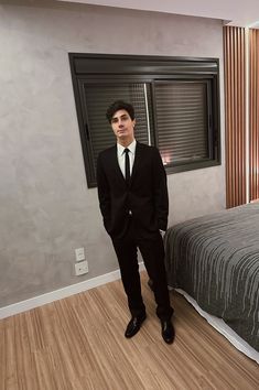 a man in a suit standing next to a bed