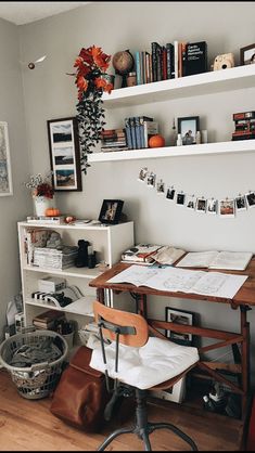 a desk with some books and pictures on the wall above it, along with other items