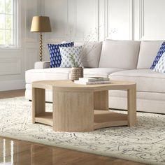 a living room with white couches and blue pillows on the floor, along with a coffee table