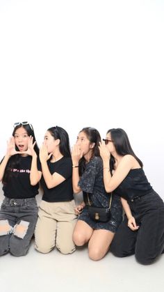 four young women sitting on the ground with their mouths open and one woman covering her mouth