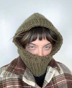 a woman wearing a green knitted hat and scarf over her face with the hood up