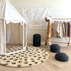 a white tent sitting on top of a hard wood floor next to black rocks and a rug