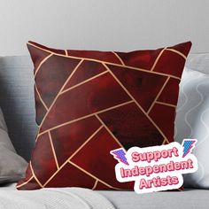 a red and gold pillow with the words support independent artists on it