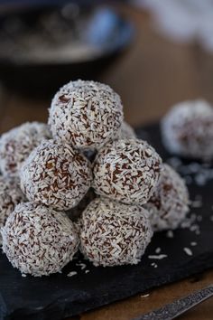 a pile of chocolate truffles sitting on top of a black plate next to a knife