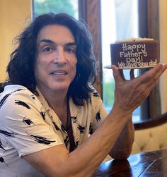 a man sitting at a table with a cake in front of him that says happy father's day