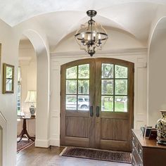 an entry way with two doors and a chandelier