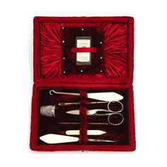 an open red velvet case with scissors and other items