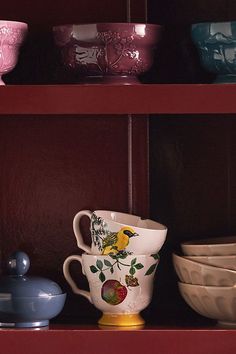 the shelves are filled with colorful dishes and glassware, including one yellow bird mug