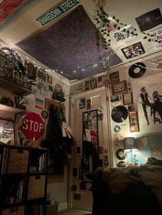 a room filled with lots of clutter and pictures hanging on the wall next to a bed