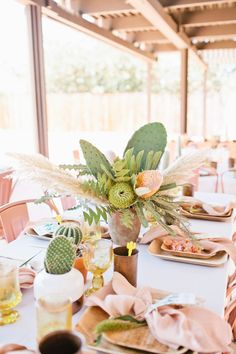 the table is set with plates, napkins and cactus plants in vases on them