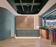 an office lobby with wooden floors and green walls, along with planters on either side of the wall