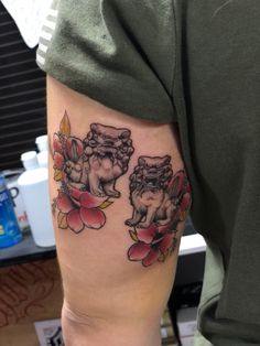 a man's arm with two cherubs on it and flowers in the background