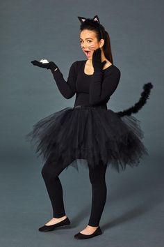 a woman wearing a black cat costume and holding something in her hand while posing for the camera