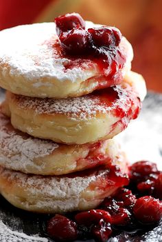 a stack of cranberry filled donuts sitting on top of a plate covered in powdered sugar