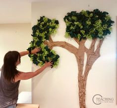 a woman is painting a tree on the wall