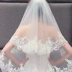 the back of a woman's wedding dress with a veil on her head and shoulder