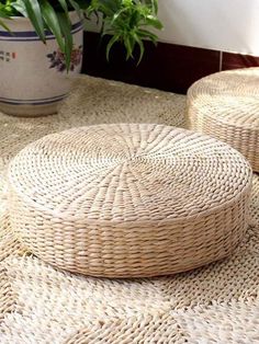 two round wicker baskets sitting on top of a rug next to a potted plant