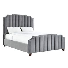 an upholstered bed with white pillows and gray linens on the headboard