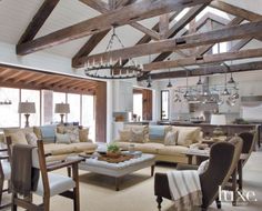 a living room filled with furniture and lots of wood beamed ceiling beams in an open floor plan