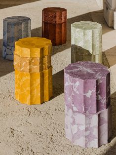 four different colored stools sitting in the sand