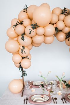 an arch made out of balloons with flowers and greenery on the top is shown