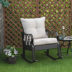 a chair and table sitting on the grass in front of a trellis with flowers