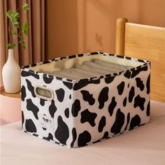 a black and white cow print storage box on a table with a vase in the background