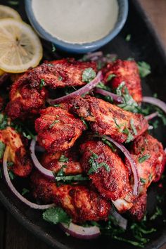 chicken wings with red onions and cilantro on a black plate