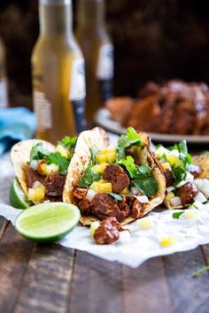 two tacos with meat, corn and cilantro are on a wooden table