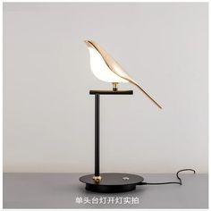 a table lamp with a white bird on it's head and a black base