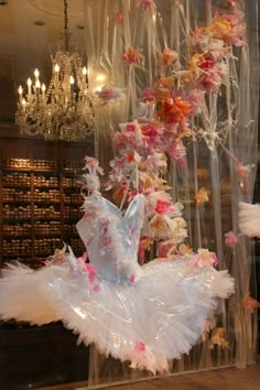 a ballerina in white tutu with pink and orange flowers hanging from the ceiling