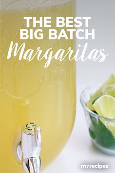 the best big batch margaritas recipe in a mason jar with lime wedges next to it